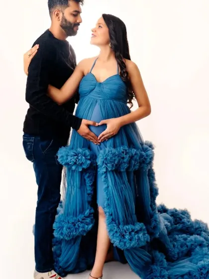 A romantic couple's portrait, with the partner's hands forming a heart on the baby bump. The mom-to-be is wearing our blue ruffled gown.