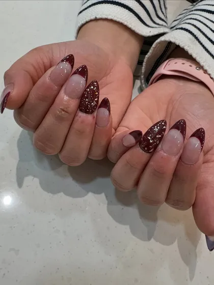 Another view of our maroon and glitter French design, showing how the light catches the sparkling accent nail.