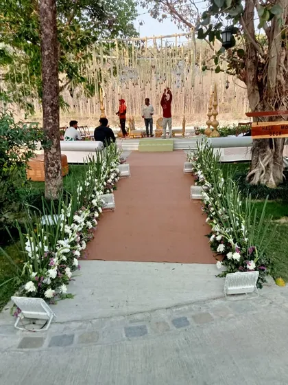 The entrance aisle for a day wedding, lined with beautiful white and green floral arrangements, leading guests to the main event area.