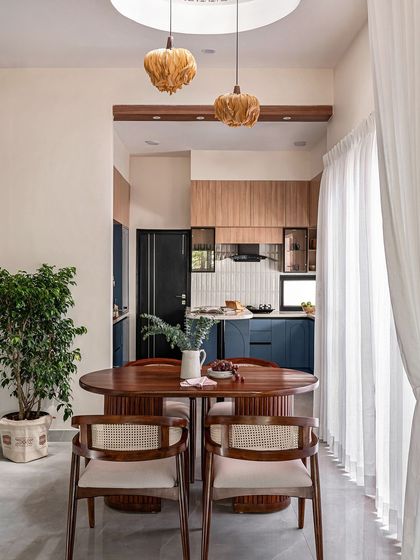 This cozy dining nook is situated right next to the kitchen, perfect for intimate family meals. The oval wooden table and cane chairs are illuminated by unique, textured pendant lights, creating a warm and inviting atmosphere.