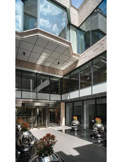 A high-angle view of the entrance courtyard, showing the multi-level glass façade that surrounds the open space and allows light to penetrate deep into the building.