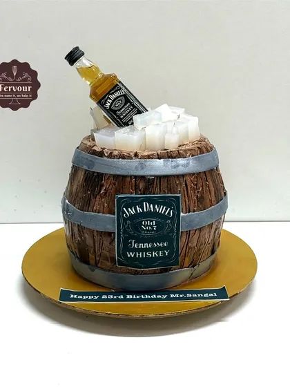 A Jack Daniel's barrel theme cake for a 23rd birthday. This cake is designed to look like a wooden whiskey barrel with a miniature bottle on top.