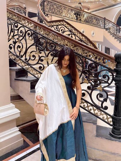 Elegance in a teal anarkali suit with a contrasting white and gold dupatta. The grand staircase adds to the royal feel.