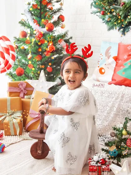 Full of festive cheer. This little girl is having a wonderful time playing in my Christmas setup, complete with trees, gifts, and a fun rocking horse.