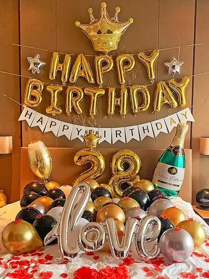 A similar bedroom setup for a 28th birthday, featuring gold, black, and silver balloons, 'LOVE' and number foil balloons, and a crown to make the birthday person feel special.