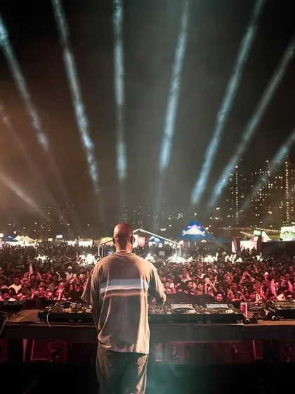A view from behind Black Coffee as he looks out onto a sea of fans, with the city lights twinkling in the background.