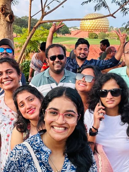 A happy group selfie at Auroville, near Pondicherry, with the golden Matrimandir visible in the background.