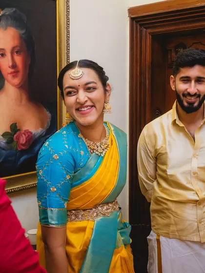 A smiling bridesmaid in her stunning yellow and blue Kanjeevaram silk saree. We believe in finding outfits that make the wedding party feel as special as the bride and groom.