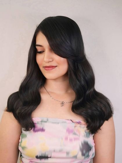 A portrait of the long layered haircut, featuring a side part and soft waves that frame the face beautifully.