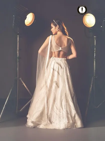 The back of this ivory lehenga is just as stunning as the front, featuring a sheer panel and delicate detailing for a touch of modern allure.