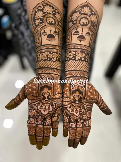 A detailed look at a symmetrical bridal design. The arms feature elephants and hanging jhumkas, while the palms have a unique, ornate pattern.