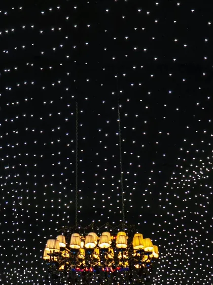 Looking up at the vast expanse of the fairy light ceiling, with a chandelier creating a central point of focus.
