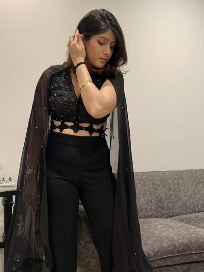 A closer look at the details of this black cape outfit. The intricate top and flowing cape create a look that is both powerful and feminine.