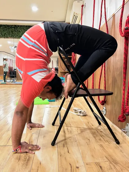Using a chair for support allows this student to work on a deep backbend, opening the shoulders and thoracic spine. This is a perfect example of prop-assisted Vrischikasana practice.