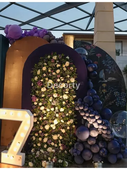 A section of the backdrop featuring a large floral arch and an illuminated number '7'.