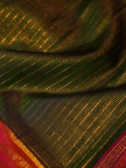 The texture of the gold zari checks on the green silk, a subtle yet luxurious detail.