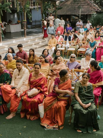 Guests dressed in beautiful, colorful sarees watch the wedding ceremony from their seats on the lawn.