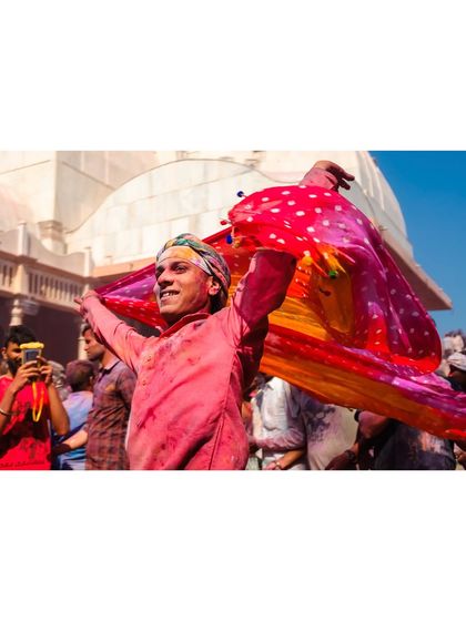 Another angle of the young man dancing with his vibrant scarf during Holi. His joyful expression and the flowing fabric create a dynamic and uplifting image.
