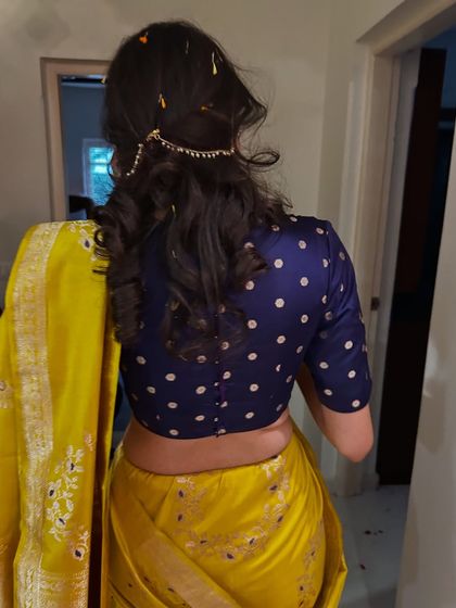 The back view of the outfit, showing a modern polka-dotted blouse paired with a traditional yellow saree. This highlights our skill in mixing classic and contemporary elements for a balanced look.