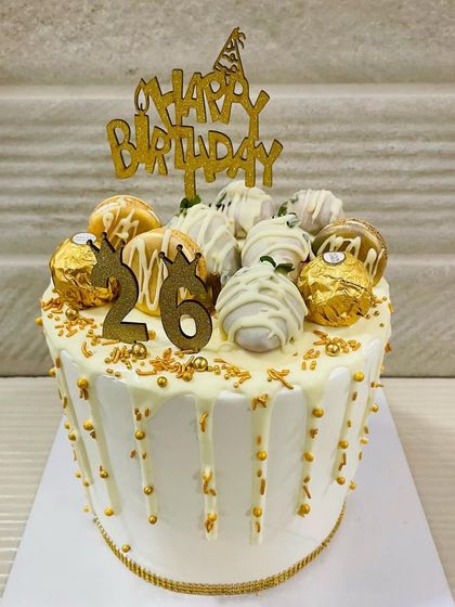 A beautiful white and gold drip cake for a 26th birthday. This elegant design is topped with white chocolate-covered strawberries and Ferrero Rocher for a touch of luxury.
