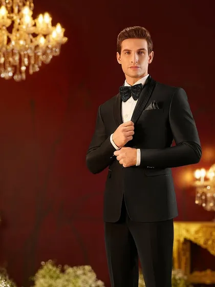 A classic black tuxedo styled for a Louis Philippe royal weddings campaign. The focus was on creating a look of timeless elegance through sharp tailoring, a peak lapel, and a perfectly knotted bow tie, set against a luxurious, warmly lit backdrop.