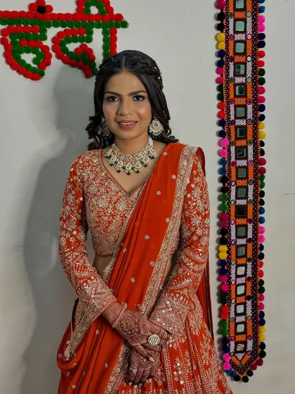 Ready for her Mehendi and engagement. The vibrant orange lehenga is paired with a soft, glowing makeup look and a beautiful braided hairstyle.
