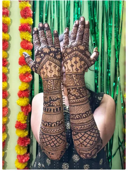 A happy bride showing off her full bridal mehendi. The design goes up to the elbows with geometric and floral patterns, perfect for her wedding ceremony.