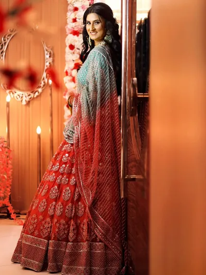 A full-length portrait of the bride-to-be, showcasing her stunning pink and blue lehenga and her happy, confident smile.
