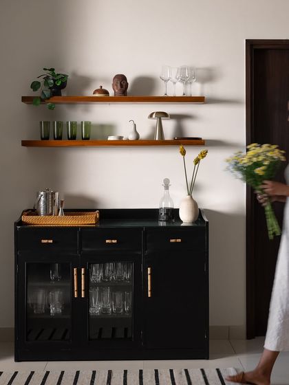 I placed this simple and efficient bar unit in the transition space between the living, dining, and kitchen areas to act as a subtle visual separator. Finished in a classic black with elegant handles, it offers plenty of storage for our clients who love to host.