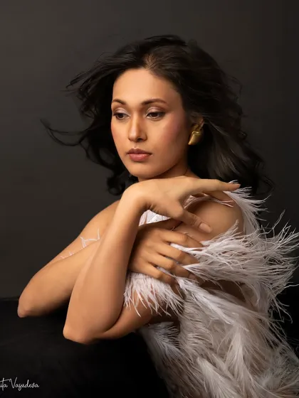 A more pensive and artistic shot from the same feathered look. The wind in her hair and her thoughtful expression create a portrait that feels like a painting.