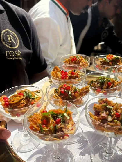 A server presents a tray of Palak Patta Chaat in elegant coupe glasses. This modern presentation of a classic dish exemplifies our commitment to combining fresh ingredients with artistic flair.