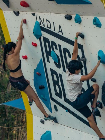 The Psicobloc India logo is a prominent feature on the wall, seen here as two climbers compete. The event brings together the best of bouldering and water sports.