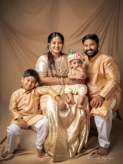 A full family portrait in traditional golden outfits. Everyone is smiling, creating a beautiful and happy memory.