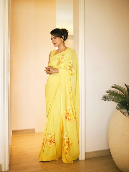 A full-length view of the yellow saree, demonstrating its graceful drape and flow.