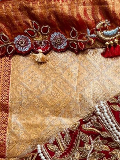 A detailed view of the custom tassels on this red bridal blouse, featuring a tiny embroidered bird. These personalized touches make each blouse one-of-a-kind.