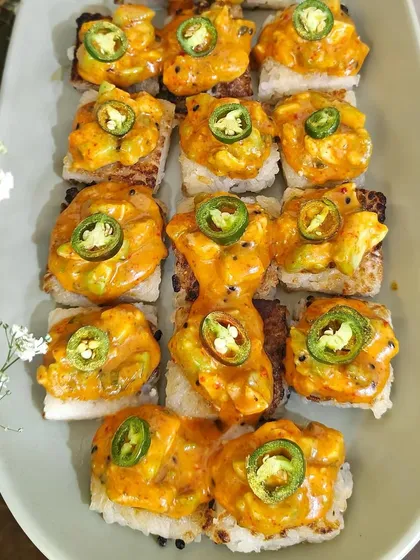 A top-down view of our spicy avocado crispy rice, garnished with jalapeños. A delicious and trendy appetizer for your T20 match screening party.