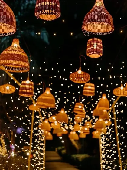 A beautiful beachside sangeet entrance in Goa, with an archway of woven lanterns and fairy lights creating a warm, bohemian glow against the night sky.