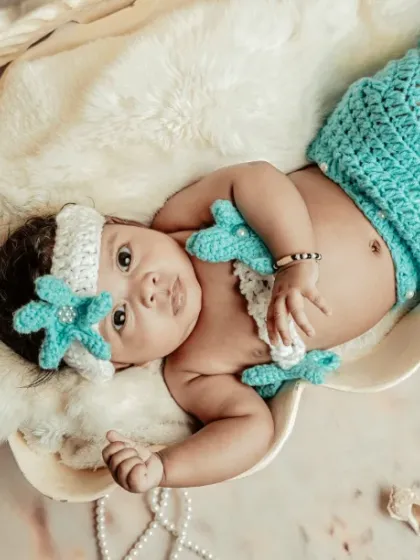 A treasure from the sea. This little mermaid theme is one of my favorites, using a knitted tail and a seashell prop to create a magical ocean scene.