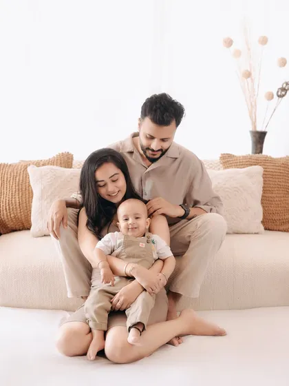 A happy family portrait filled with smiles. The baby's cheerful grin is infectious, making this a truly heartwarming image from their studio session.