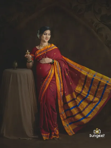 A classic pose with a traditional lamp (diya), symbolizing light and hope. This is a beautiful concept for a cultural maternity shoot.