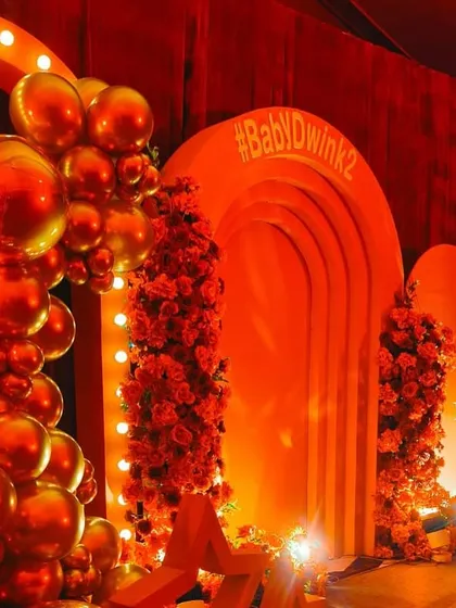 A closer view of the Bollywood themed party decor, highlighting the metallic red balloon garland and the lit marquee arch. This setup is designed to be a high impact photo opportunity for guests.