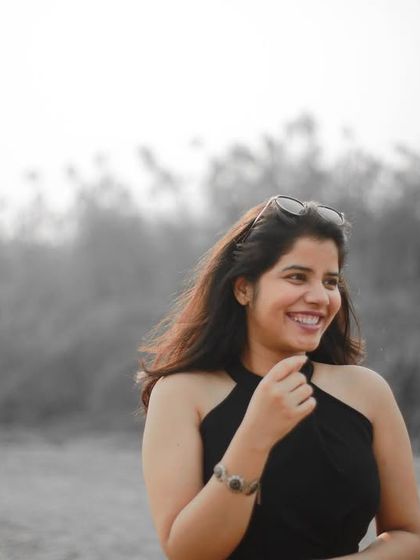 A candid and joyful shot of the bride-to-be, with the groom in the background, creating a beautiful and natural pre-wedding photograph.