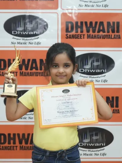A little artist proudly holds her certificate and trophy.