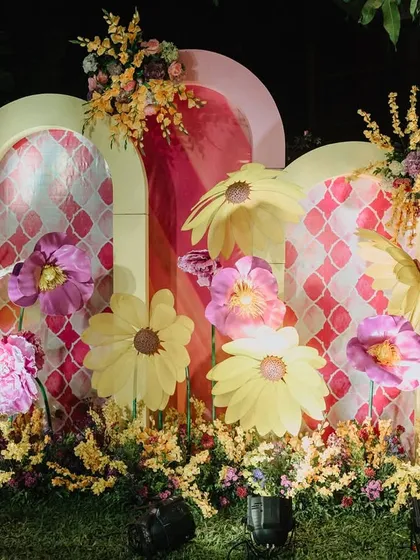 A unique Haldi-carnival photo booth. I used bold, arched backdrops with a retro pattern and adorned them with oversized, colorful paper flowers to create a fun and artistic focal point for the event.