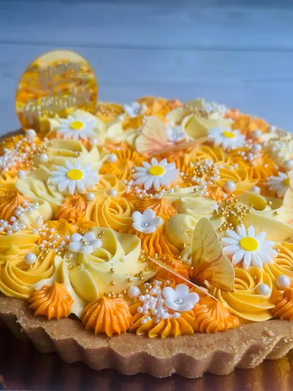 A side view of the yellow butterfly tart, showing the intricate piping work and the delicate placement of the edible decorations and sprinkles.