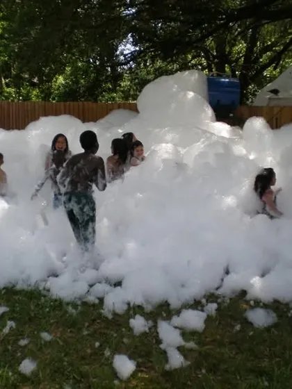 Kids having a blast in a mountain of foam at an outdoor party. This activity is pure fun and perfect for creating an energetic and playful atmosphere.