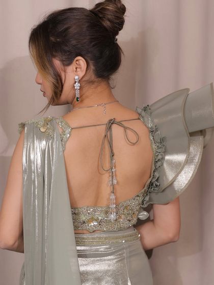 Glamour in every drape. This sage green pre-draped saree with a hand-embroidered blouse and dramatic ruffle sleeves is a true masterpiece for any wedding event.