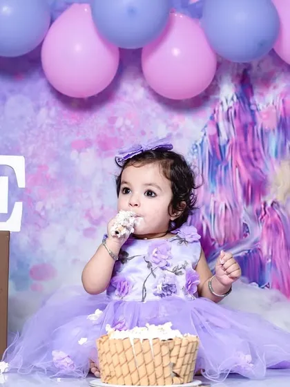 A little fairy enjoying her birthday cake. This image combines a magical fairy theme with the fun of a first birthday cake smash session.