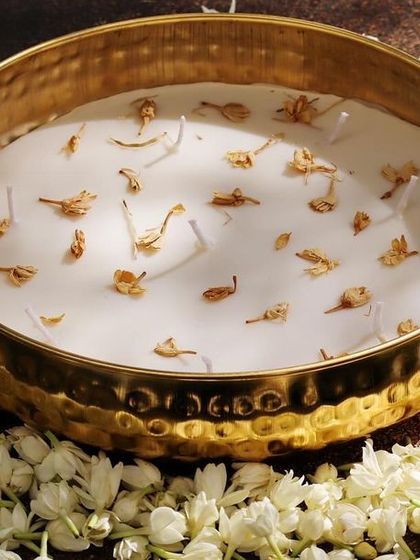 A large jasmine-scented urli candle surrounded by fresh mogra flowers. This image captures the essence of the fragrance and the elegance of the hammered gold bowl.