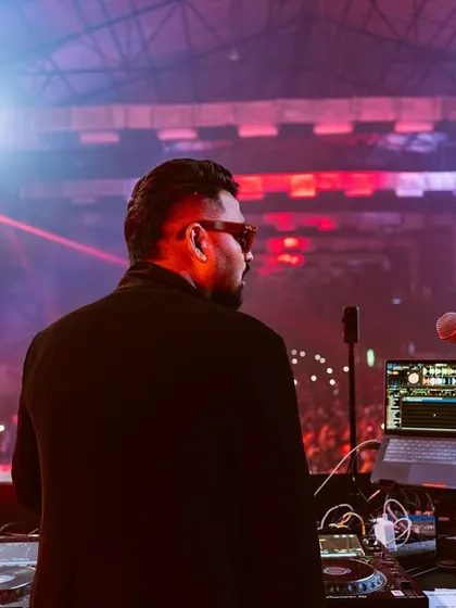 A shot from behind the decks, looking out at a packed festival ground. The mix of red and blue lights sets the mood before I drop the next track.